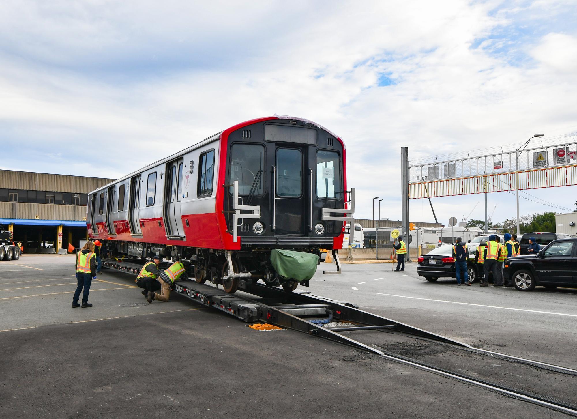 Red Line car being delievered to Cabot Yard, with MBTA workers helping to get it off the trailer.