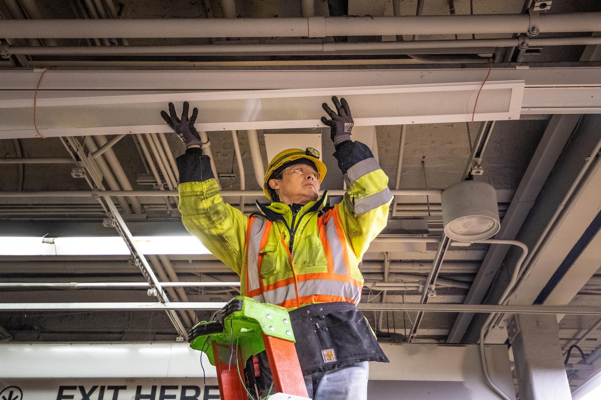A crewman installs new lights above the Green Line at Park Street