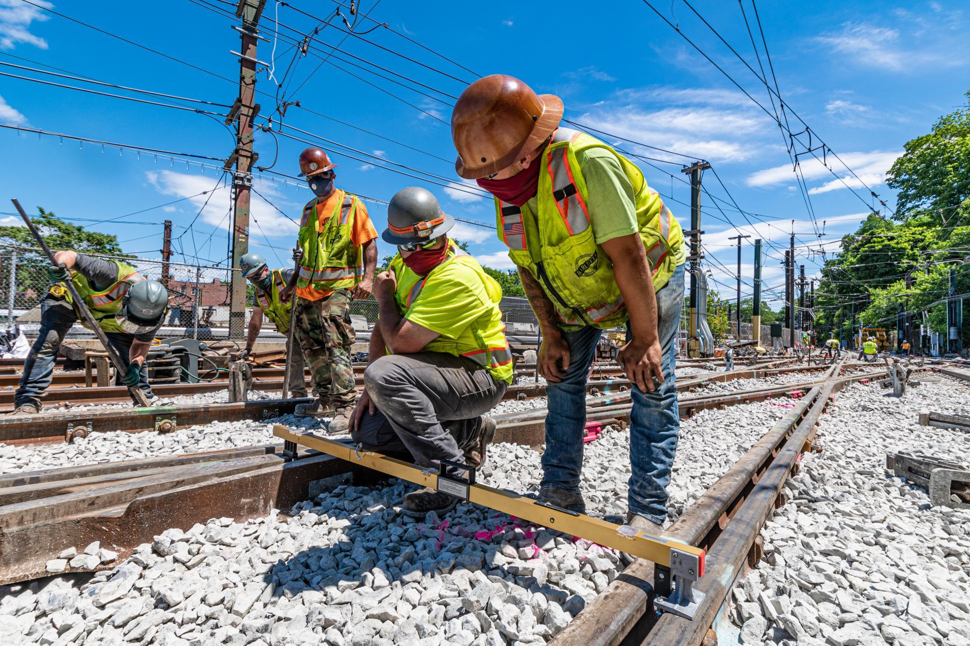 A crew aligns track and installs ballast near Reservoir Station on the Green Line D