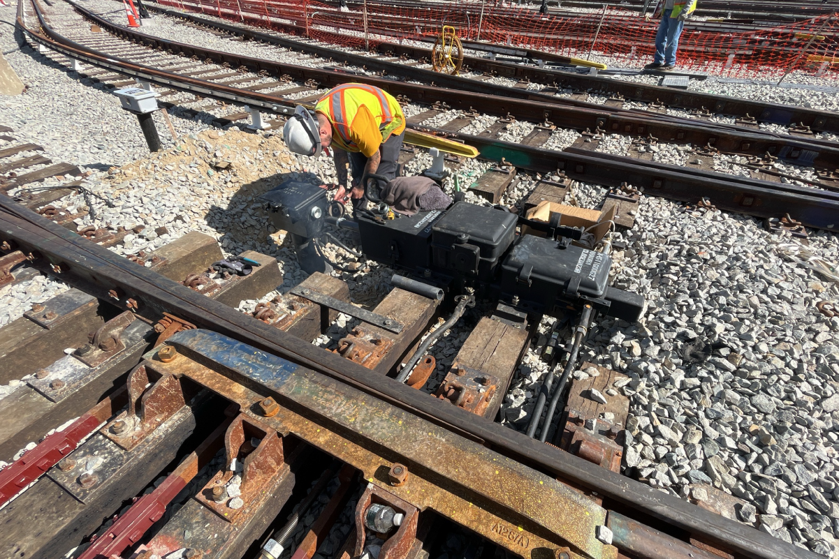 a crew member working on a switch for orange line tracks
