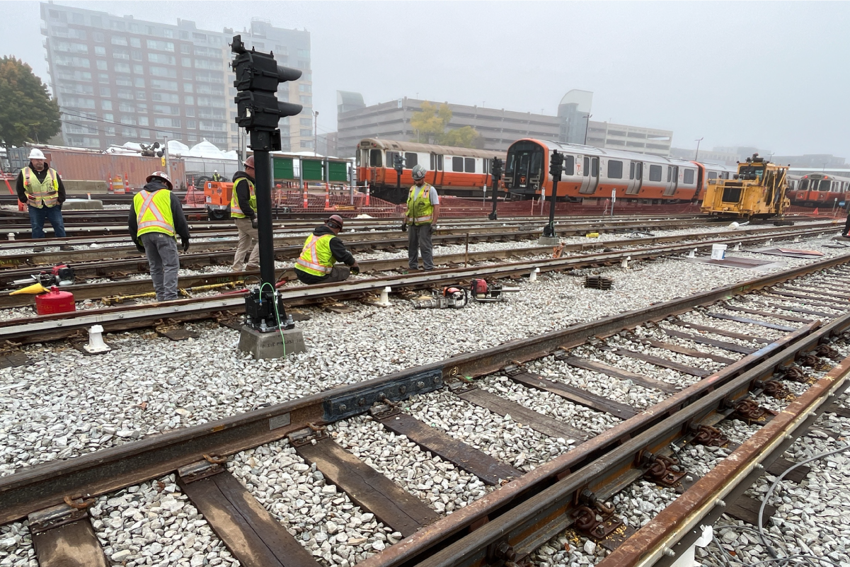 five construction crew members in reflective vests and hard hats working on tracks on a foggy day