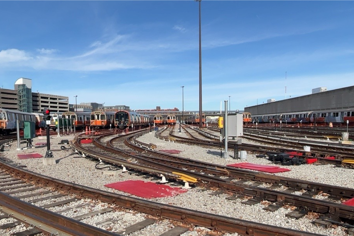 orange line trains on storage tracks under a blue sky 