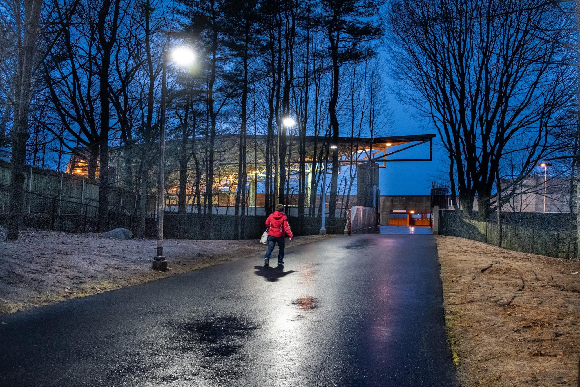 A woman walks on the paved path to the Quincy Adams gate