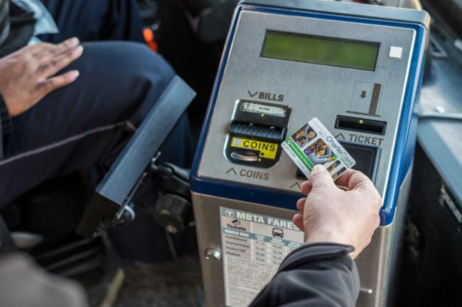 A rider taps his CharlieCard on a farebox while boarding the bus