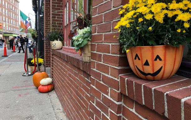 In Salem, a jack-o-lantern planter with flowers sits in a windowsill, with the weekend crowd in the background