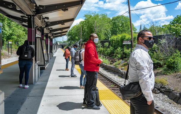 Customers at the Blue Hill Ave Commuter Rail platform, wearing face coverings